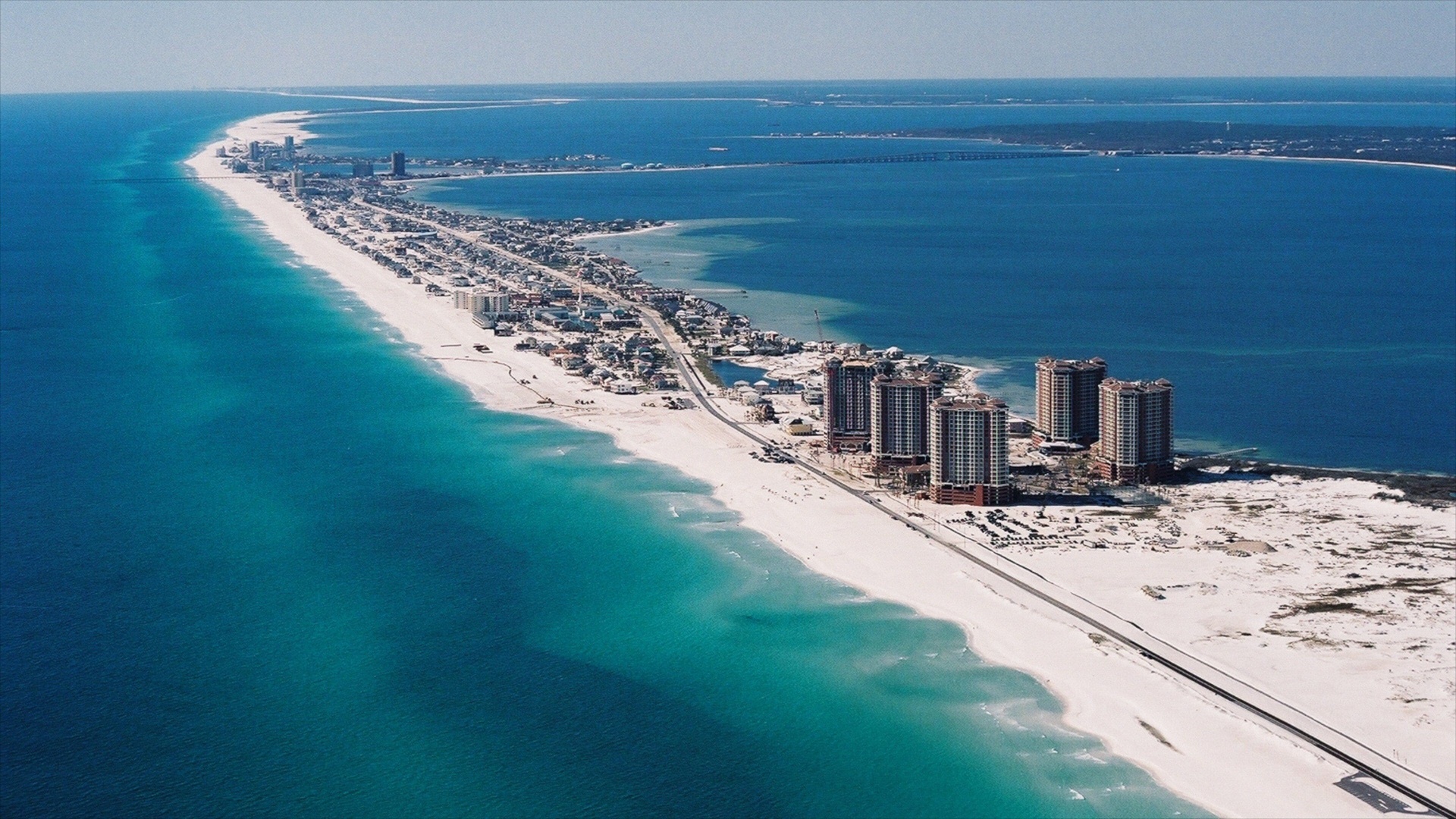 Aerial view of Pensacola Beach with turquoise Gulf water, white sand, and beachfront high-rises