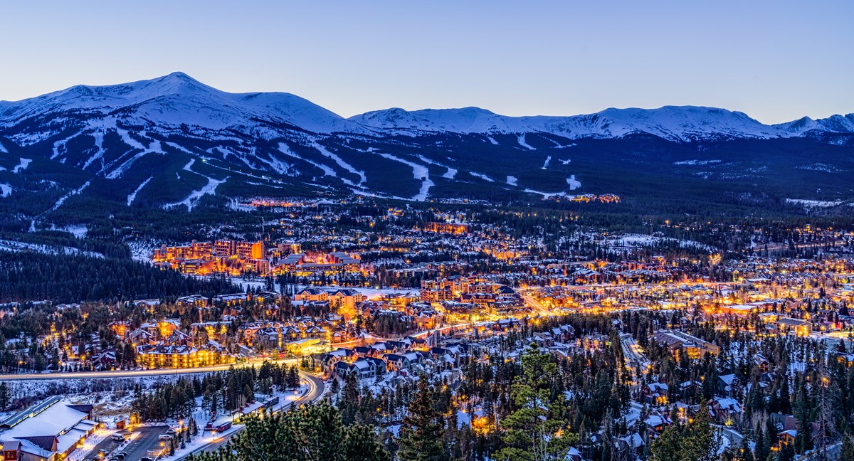Aerial view of Breckenridge town lights at dusk with Peak 8 ski runs in the background