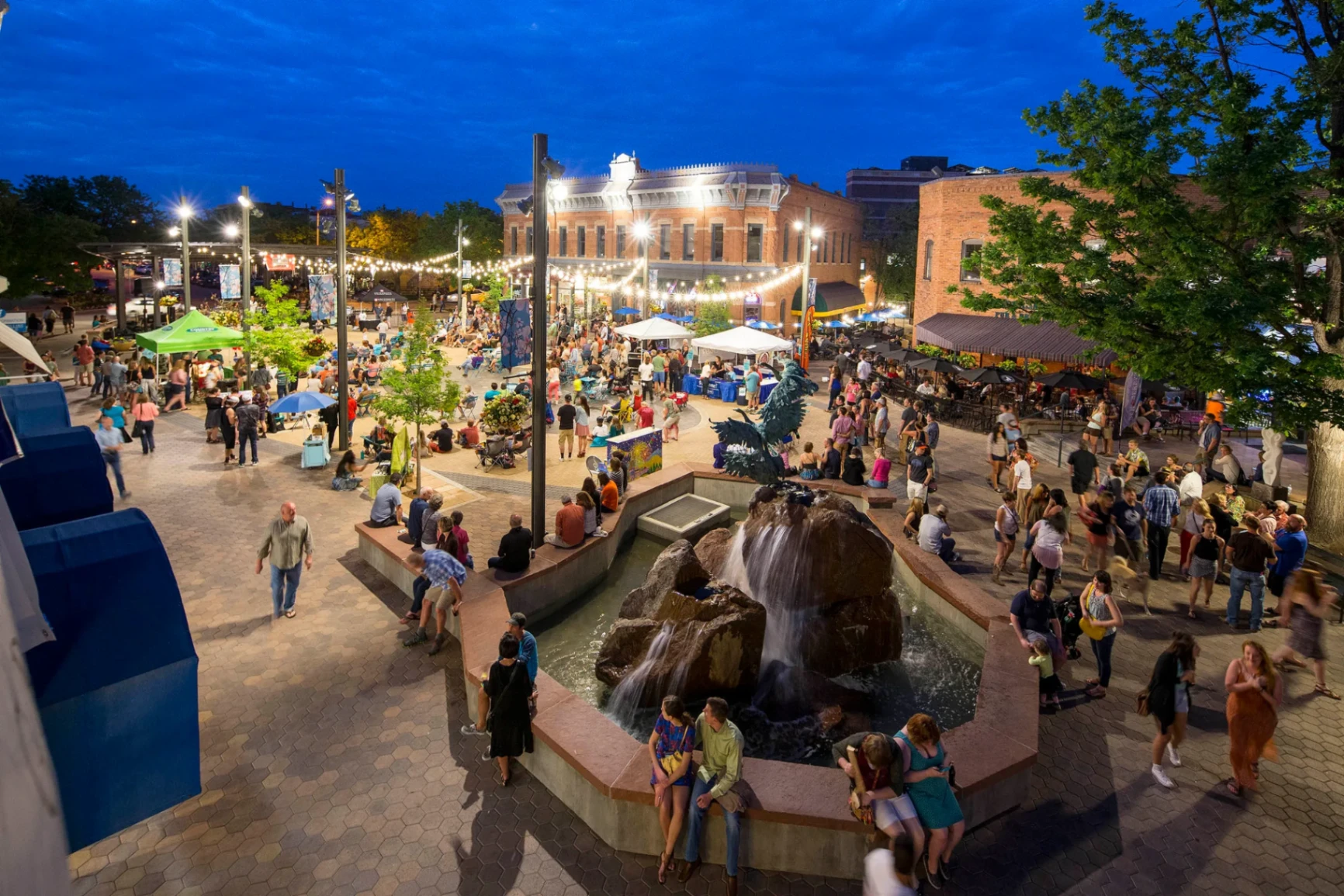Old Town Square in Fort Collins at night with crowds and string lights