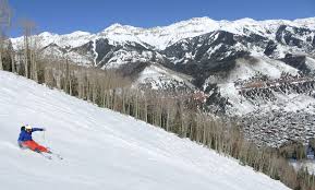 Skier carving down a Telluride ski run with the mountain village in view